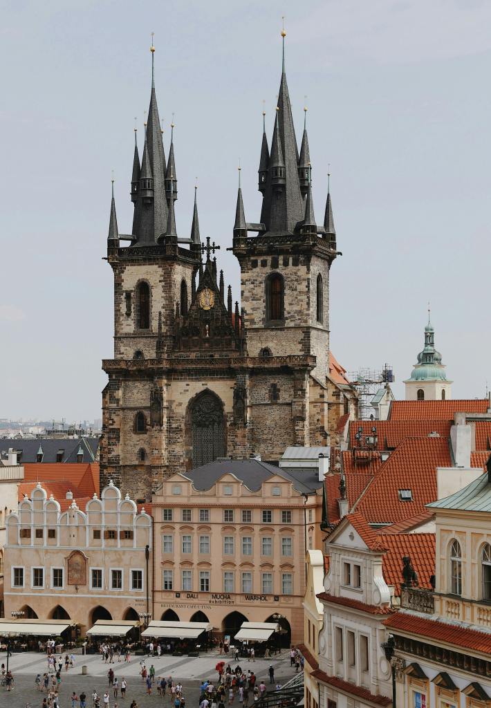 Gothic church with tall spires surrounded by historic buildings and a crowded town square
